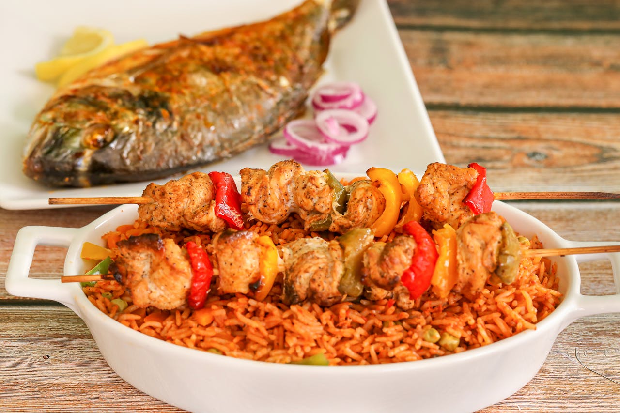 The Art of Drawing Readers In: Your attractive post title goes here Close-up of flavorful Nigerian jollof rice with grilled chicken skewers and roasted fish.
